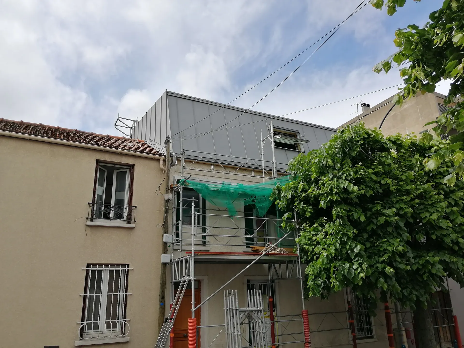 Chantier en façade d’un immeuble, échafaudage et filet de protection en place