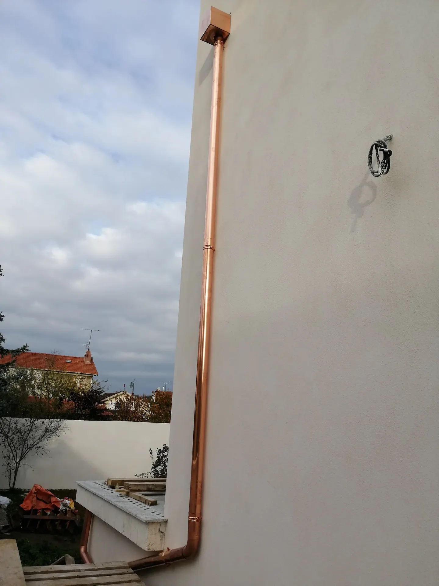 Ouvrage en cuivre posé le long d’une façade enduite
